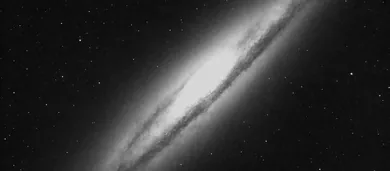A distant galaxy seen at an angle, in black and white.