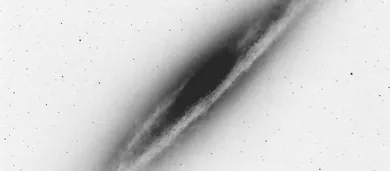 A distant galaxy seen at an angle, in black and white.